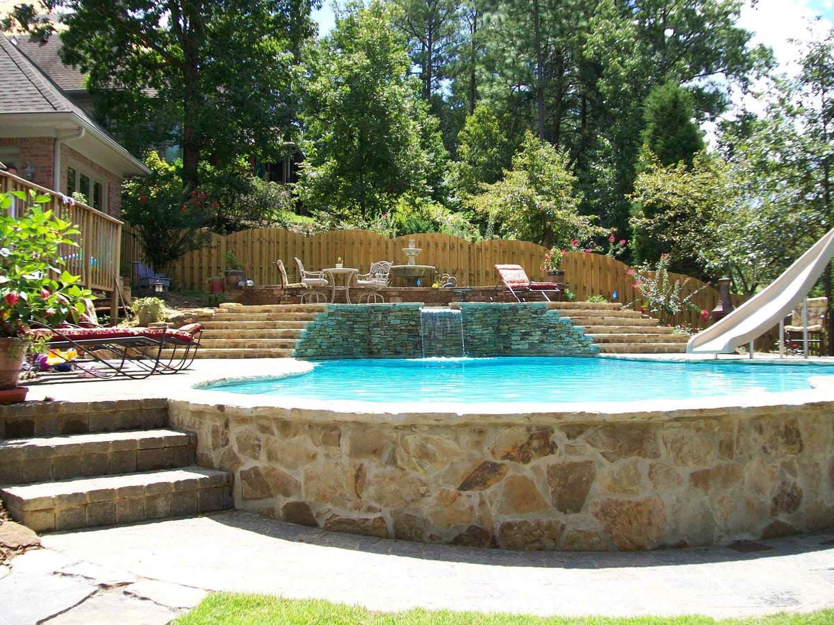Pool with stone-faced raised wall, spa waterfall, wide stone steps and slide