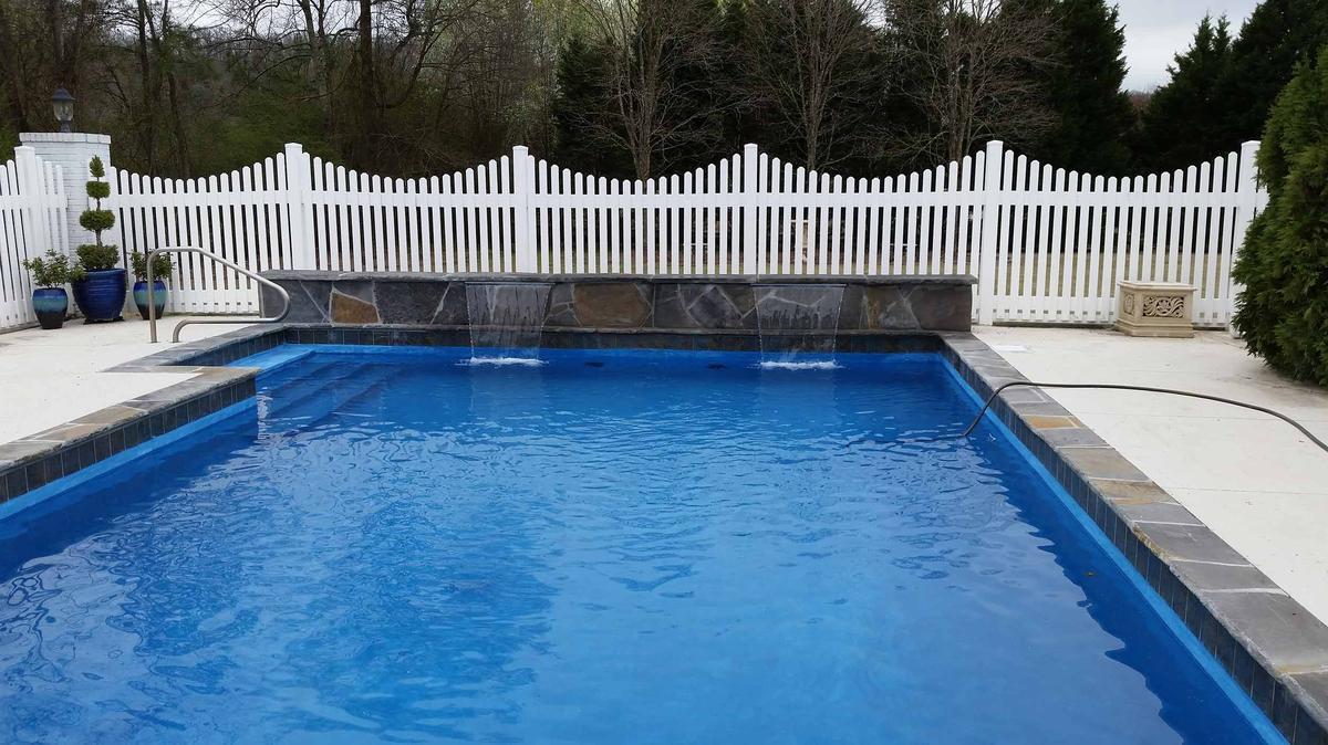 Rectangular pool with stone wall sheer descents and white picket fence