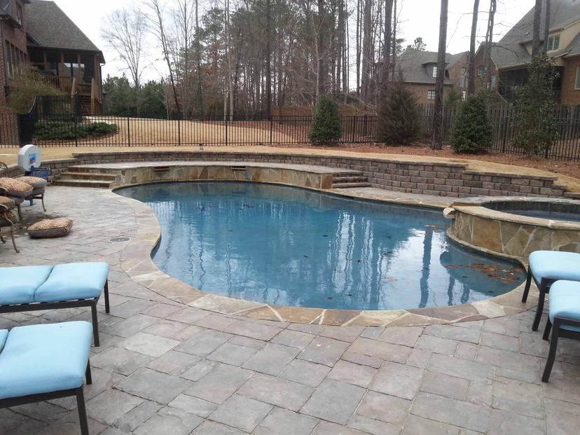 Kidney pool with raised flagstone spa, seat wall steps and paver deck